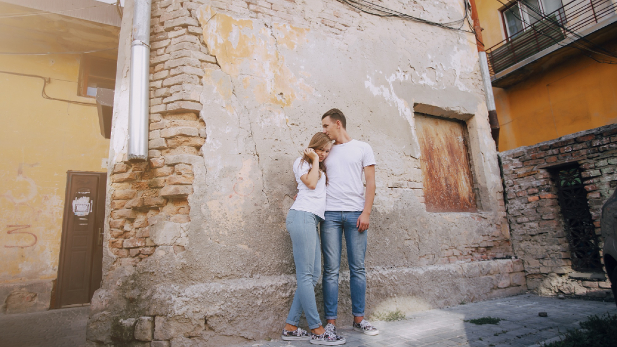 Пара молодых людей стоят на фоне каменной стены