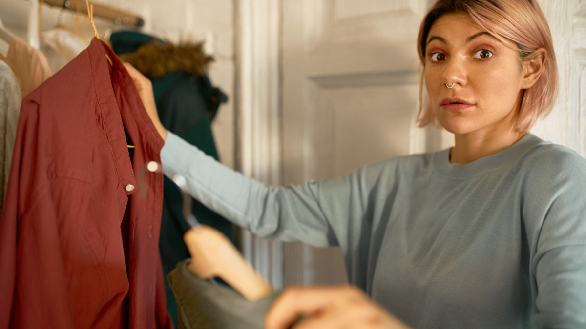 девушка держит плечики с вещами