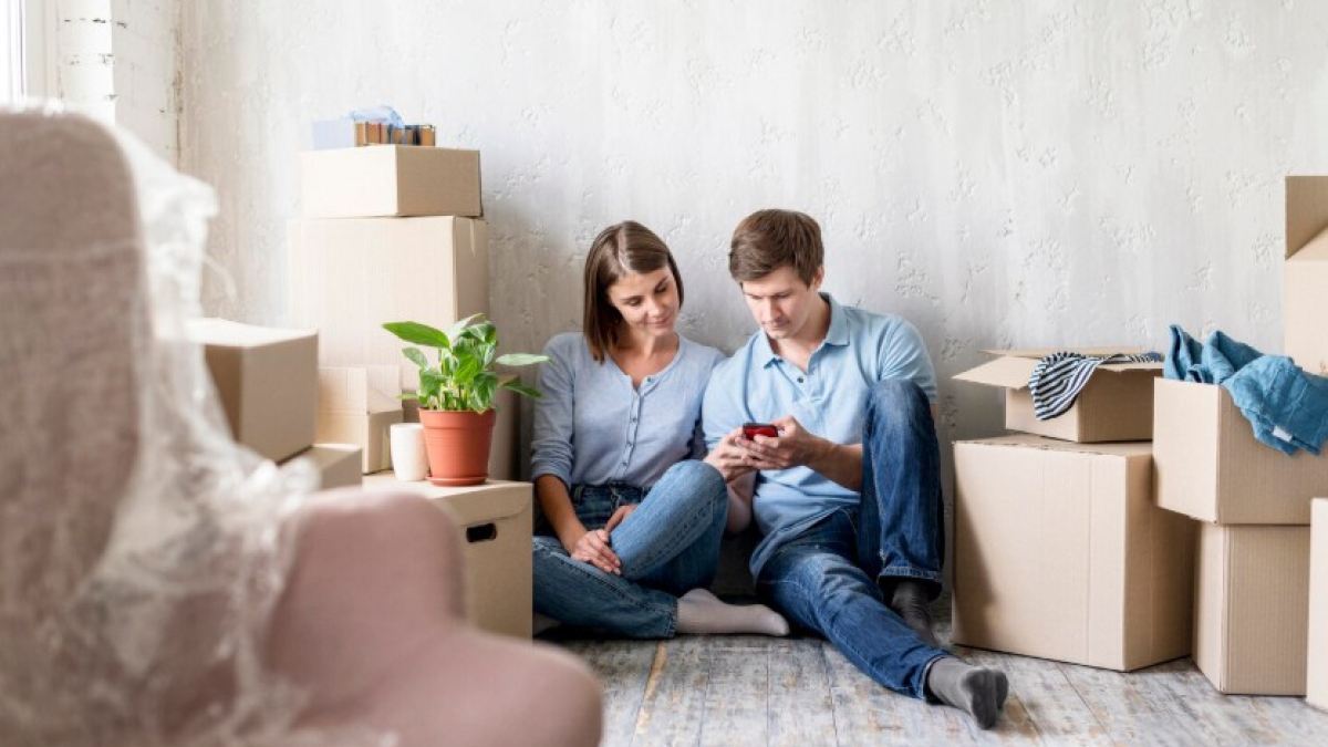 Пара смотрит в телефон посреди коробок