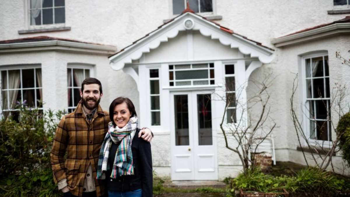 Улыбающаяся пара стоит возле дома