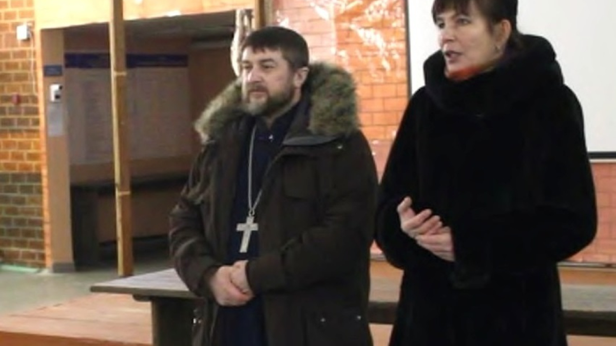 священник стоит рядом с женщиной