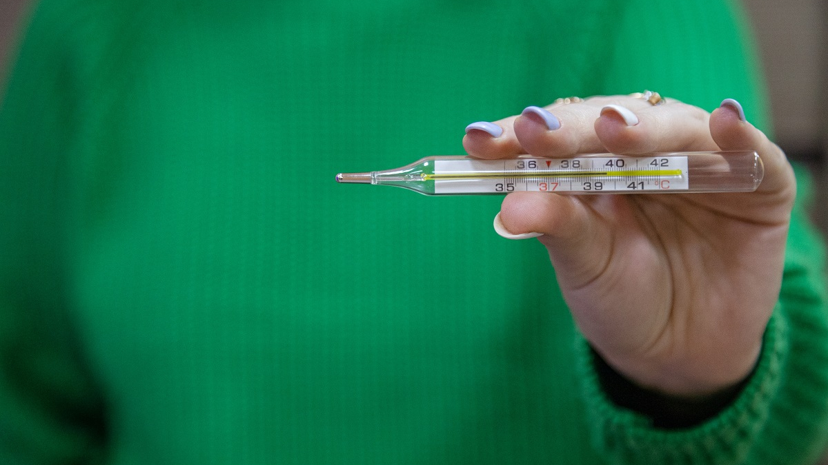 девушка держит в руке градусник