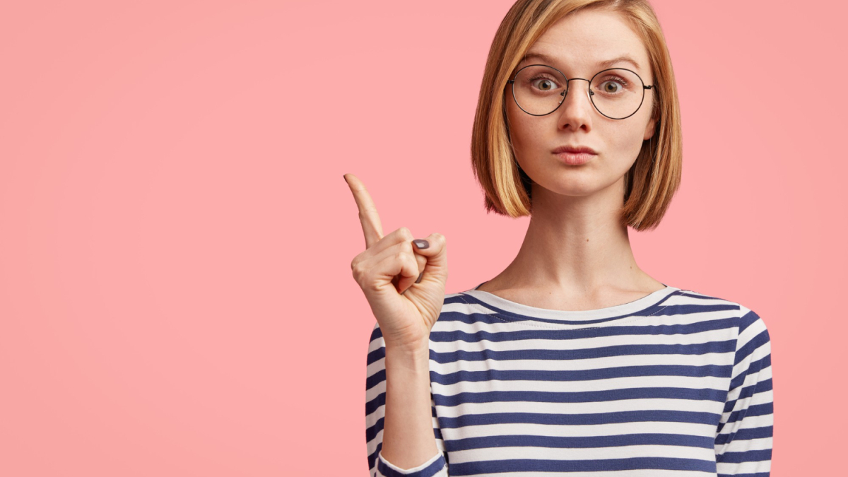 Девушка в очках с поднятым вверх пальцем