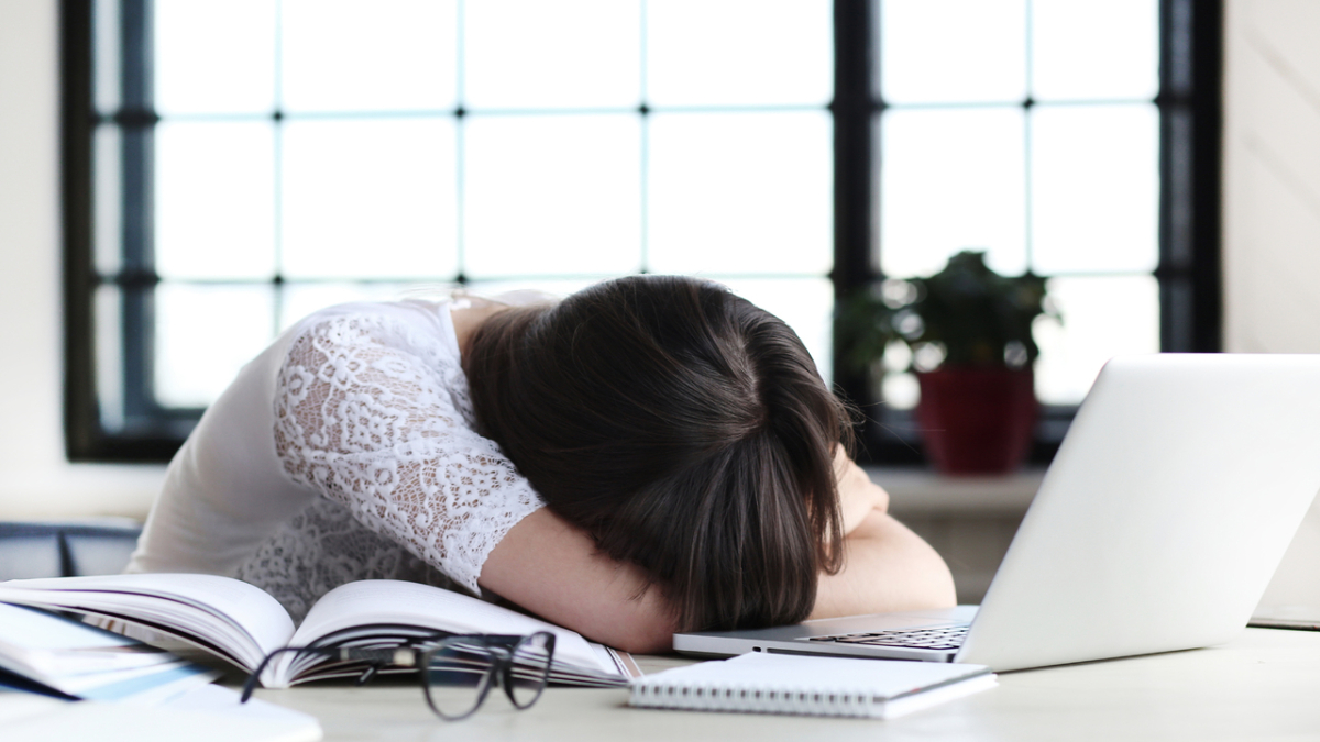 Женщина лежит на столе перед ноутбуком