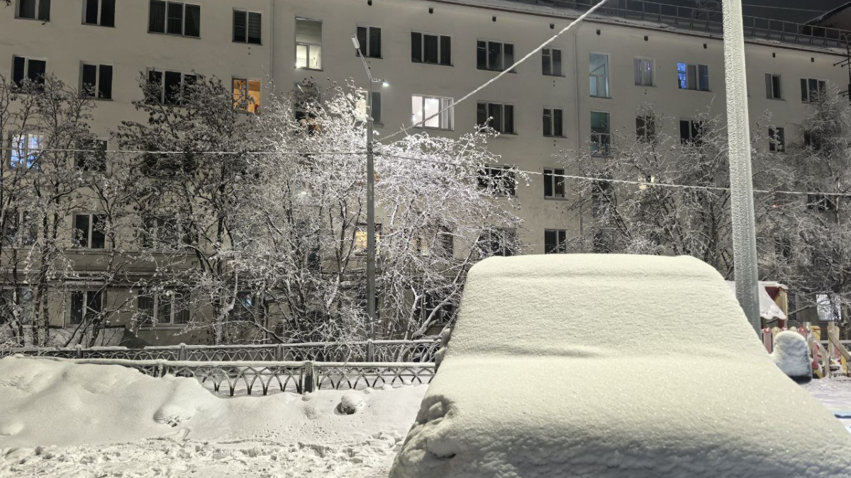 Заснеженный автомобиль на фоне пятиэтажного дома