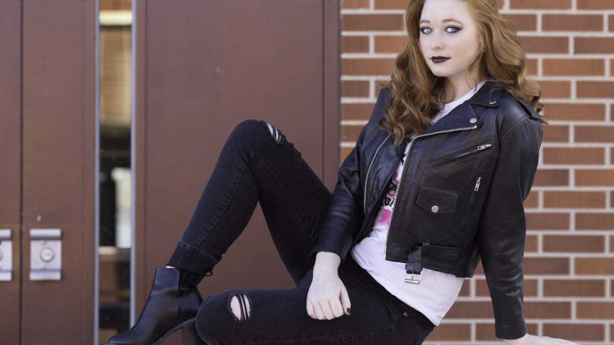 Девушка сидит на фоне кирпичной стены