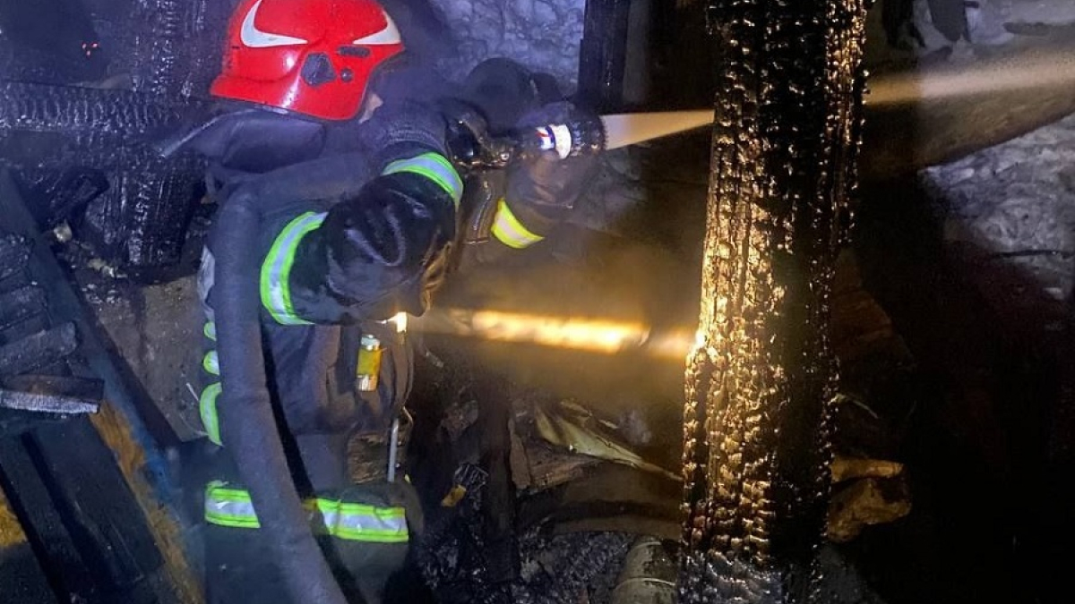 пожарный тушит деревянный дом