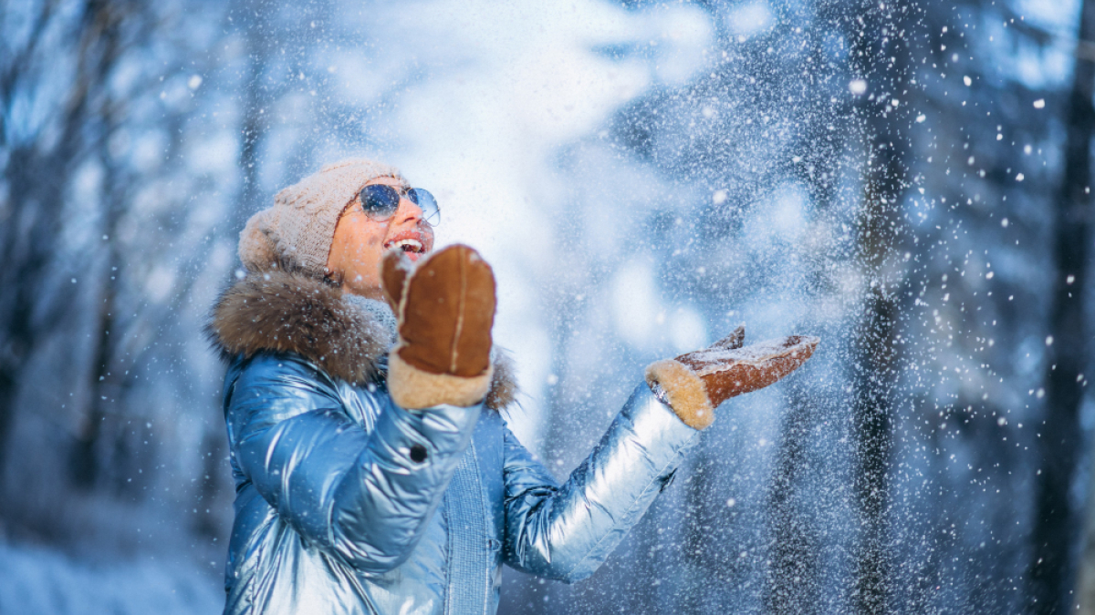 Девушка в голубой куртке радуется снегу и зимнему дню