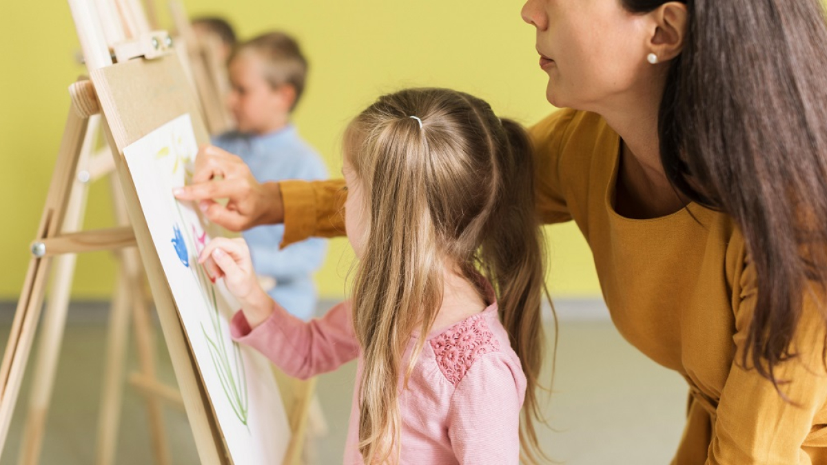 преподаватель учит ребенка рисовать