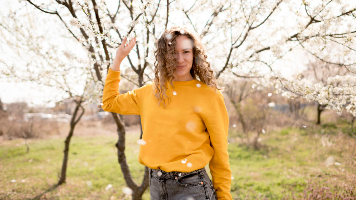 девушка в желтом свитере на фоне цветущего весной дерева