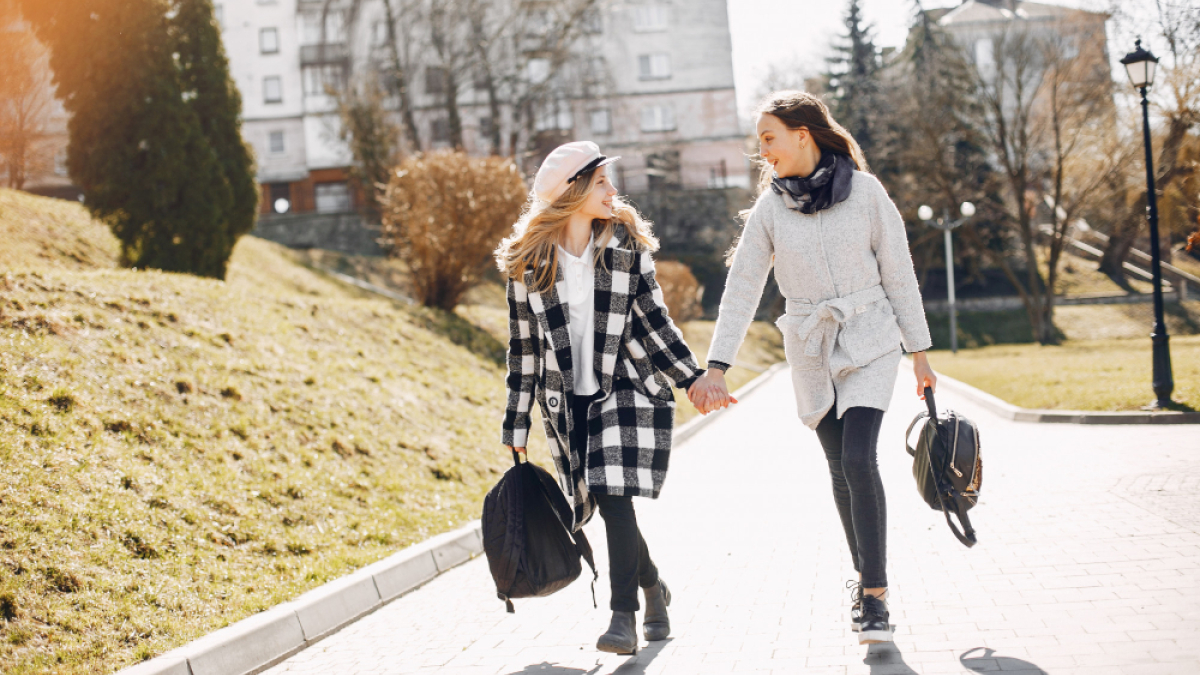 Две девушки на прогулке по парку весной держатся за руки