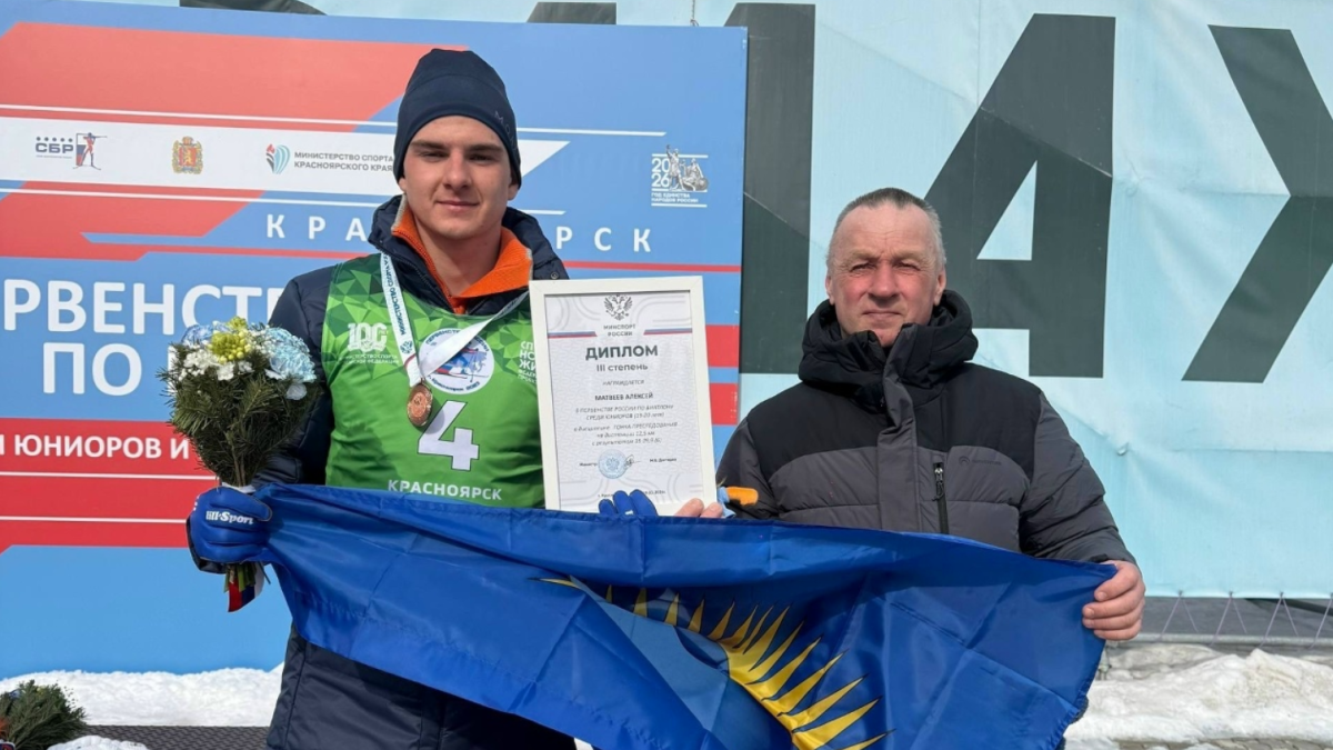 биатлонист во время награждения с тренером