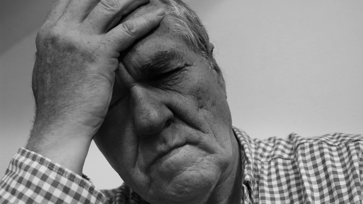 Пожилой мужчина держится за голову