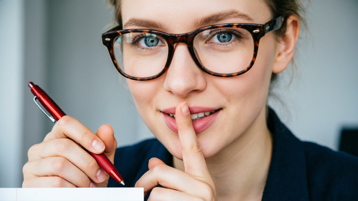 Девушка подносит палец к губам