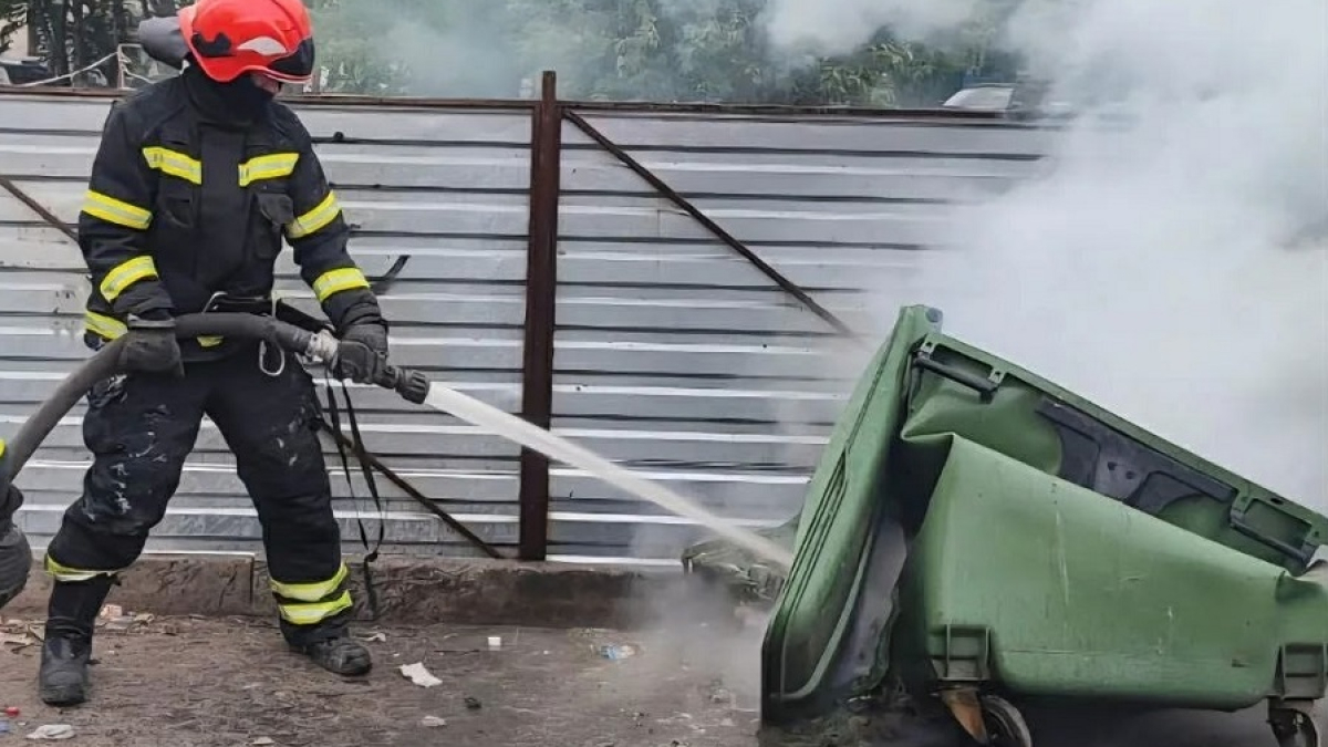 пожарный тушит мусорный контейнер