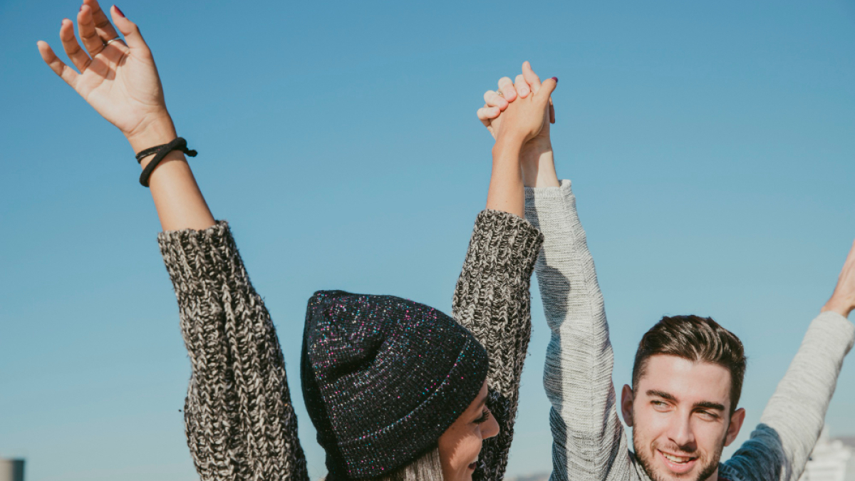 Парень и девушка смотрят друг на друга, подняв руки вверх.