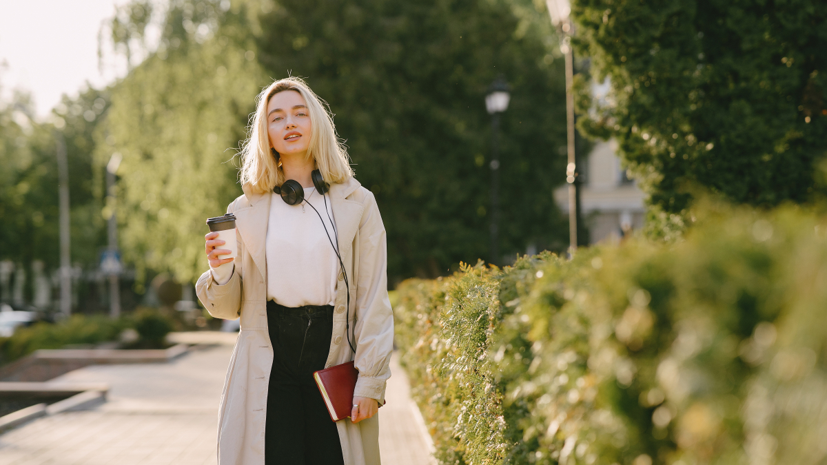 Девушка гуляет по парку со стаканчиком кофе