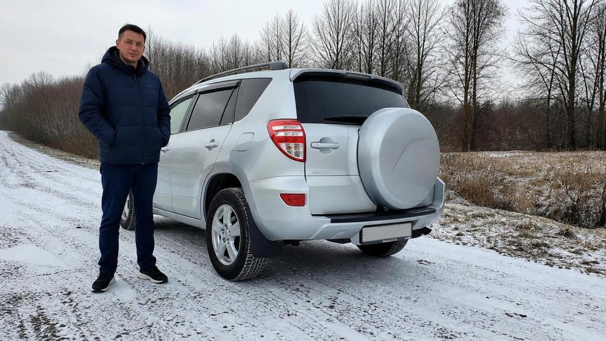 Мужчина осматривает б/у кроссовер Toyota RAV4 перед зимой