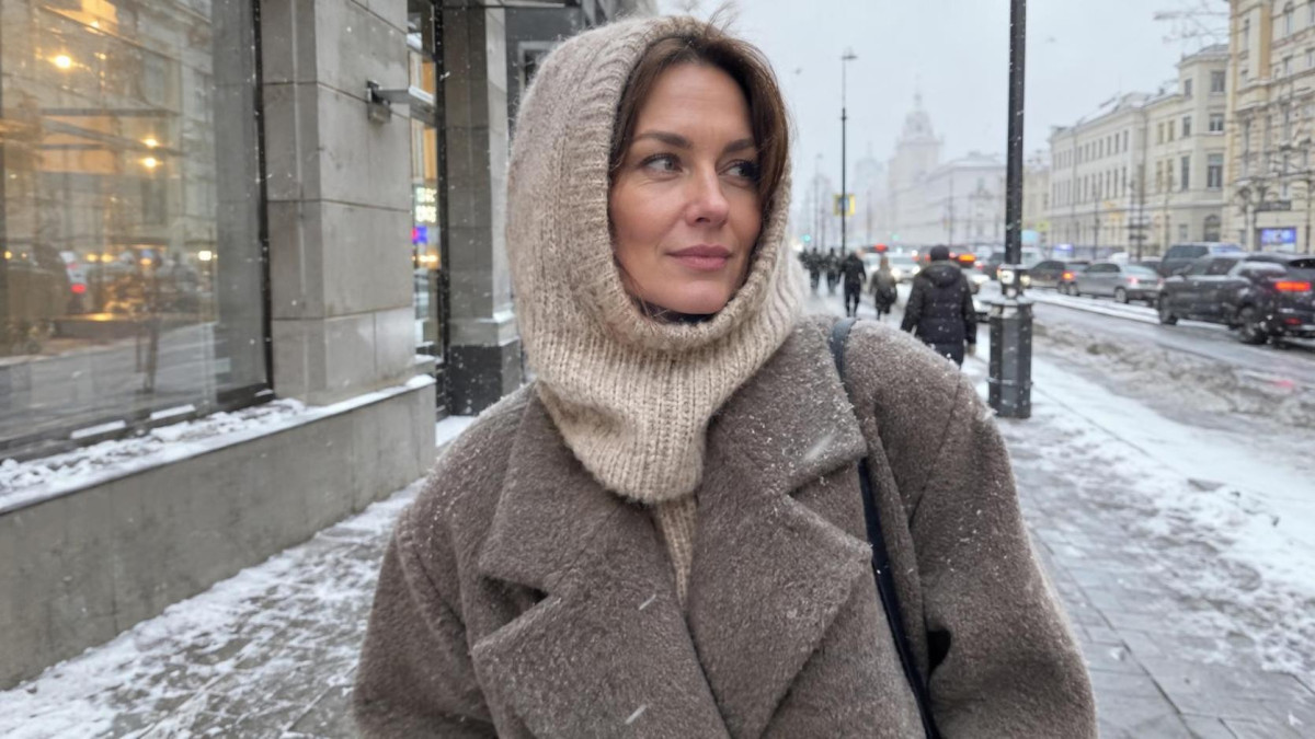 Стильная женщина в вязаном капоре бежевого цвета на зимней улице города