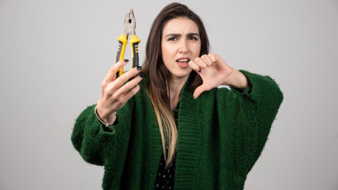 Девушка с плоскогубцами показывает большой палец вниз