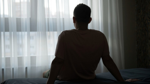 Человек на кровати перед окном