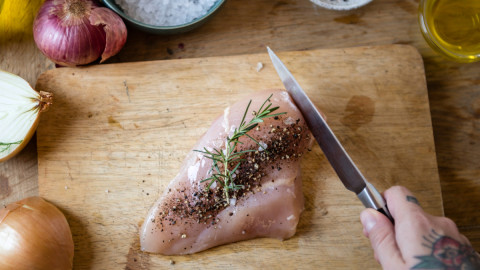 Человек режет куриную грудку