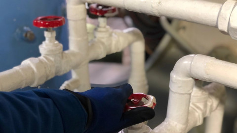 мужчина крутит кран отопления