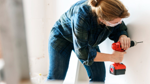 женщина сверлит стену