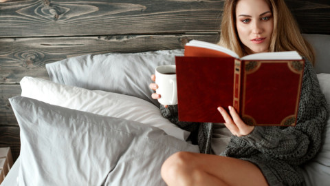 Девушка читает книгу в кровати