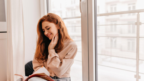 Девушка читает журнал возле окна