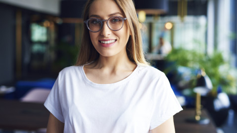 Девушка в белой футболке и очках улыбается