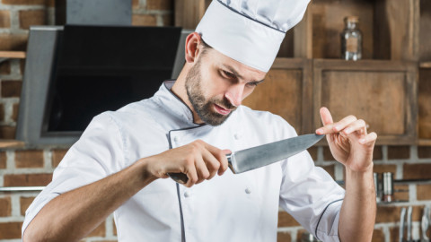 Повар рассматривает лезвие ножа