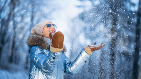 Девушка в голубой куртке радуется снегу и зимнему дню