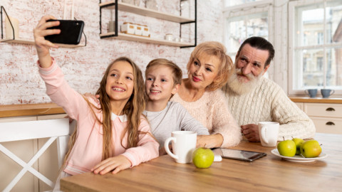 Семья фотографируется, сидя за столом на кухне