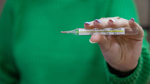 девушка держит градусник в руке