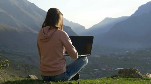 девушка за ноутбуком в горах