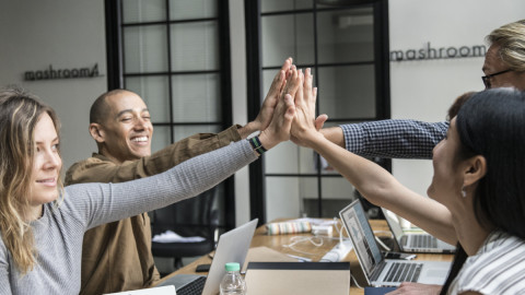 Люди соприкасаются ладонями за столом