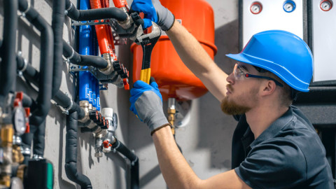 Работтник ЖКХ закрывает вентиль