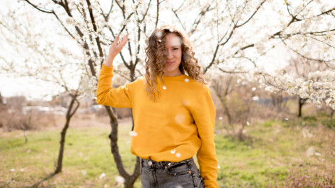 девушка в желтом свитере на фоне цветущего весной дерева