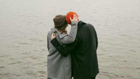 Пара стоит у воды и обнимается