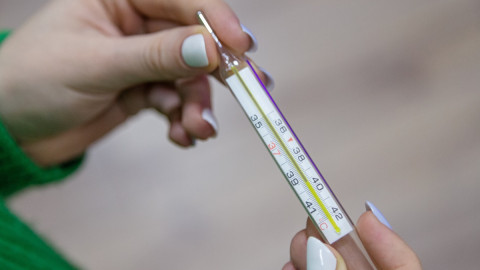 девушка держит градусник в руках