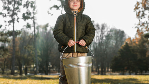 Мальчик на улице держит в руках ведро