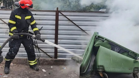 пожарный тушит мусорный контейнер