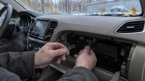 Мужчина фиксирует скрепкой тягу заслонки отопителя в салоне Lada Vesta
