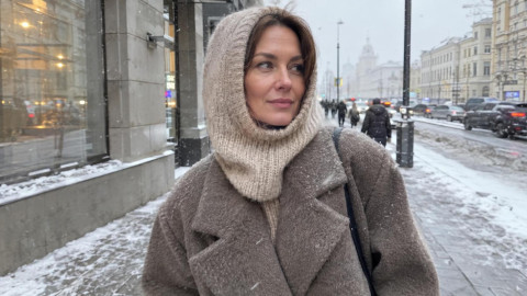 Стильная женщина в вязаном капоре бежевого цвета на зимней улице города